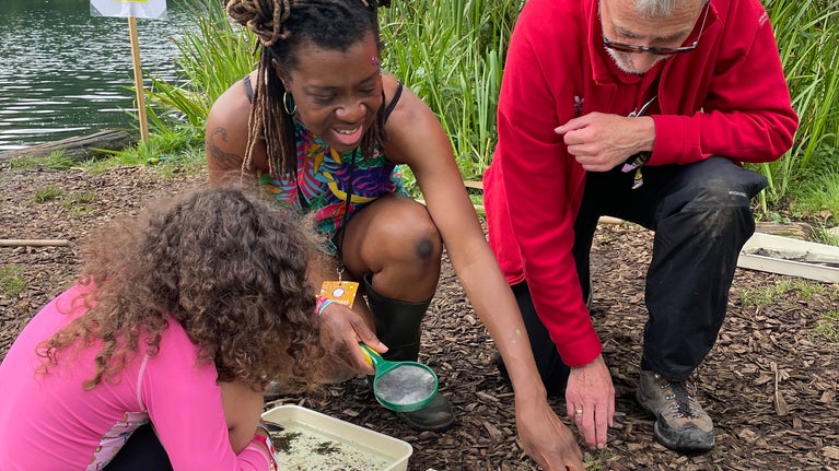Volunteer points out pond creatures to a mother and daughter